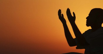 A man raises his hands to pray near the sea at sunset after a day of fasting in the holy month of Ramadan in Benghazi