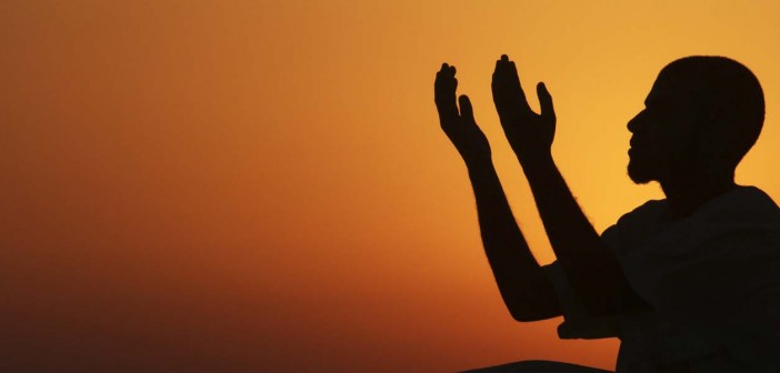 A man raises his hands to pray near the sea at sunset after a day of fasting in the holy month of Ramadan in Benghazi